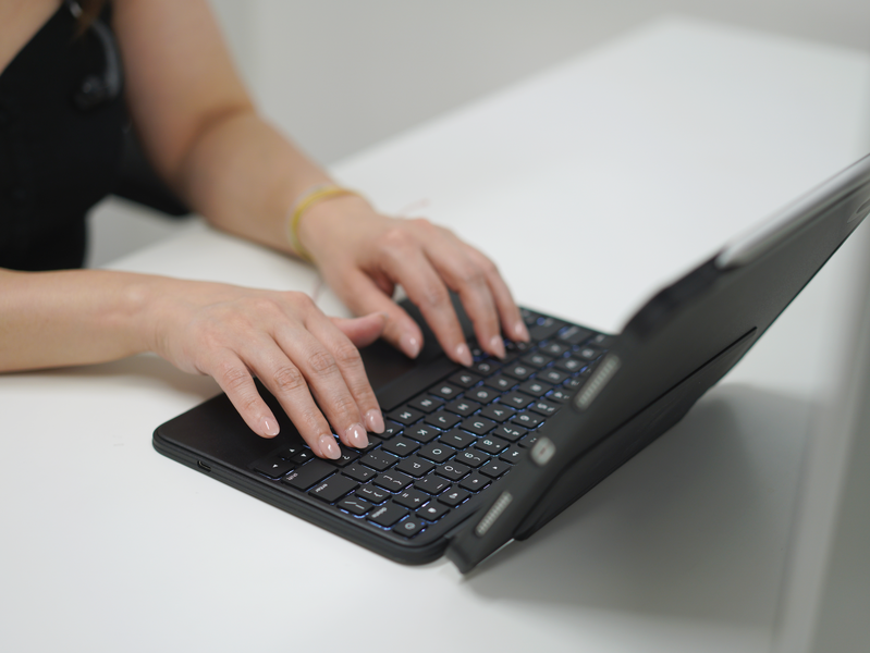 Person typing on Macally rugged iPad keyboard case with trackpad at modern desk setup