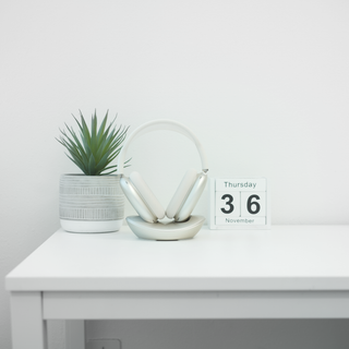 Macally AirPods Max charging stand in starlight - on a white desk with a plant