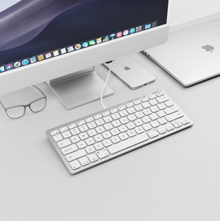 Macally portable keyboard for Mac on desk with iMac and iPhone charging via USB passthrough